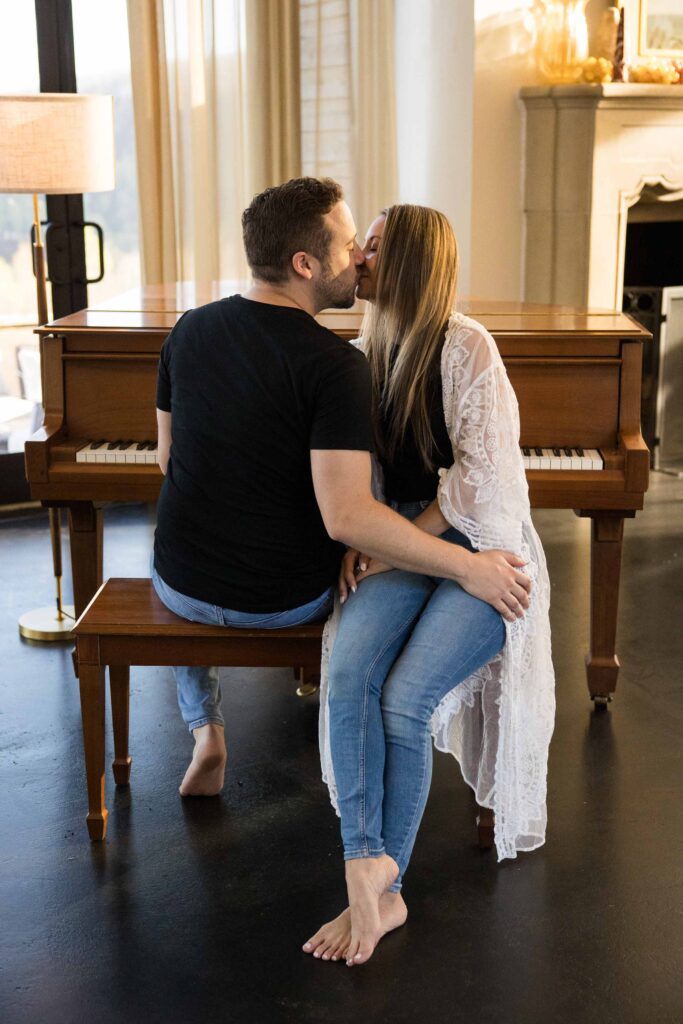 couple kisses while sitting on a piano bench during relaxed airbnb session