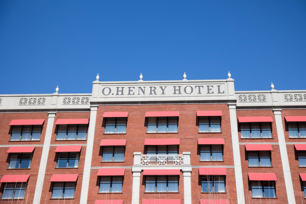 top front of the O.Henry Hotel with the sign visible against the blue sky