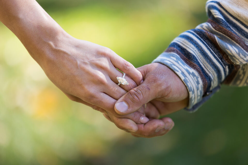 marquise shaped engagement ring on a woman's hand as she hold's her fiance's hand after their proposal at the biltmore estate
