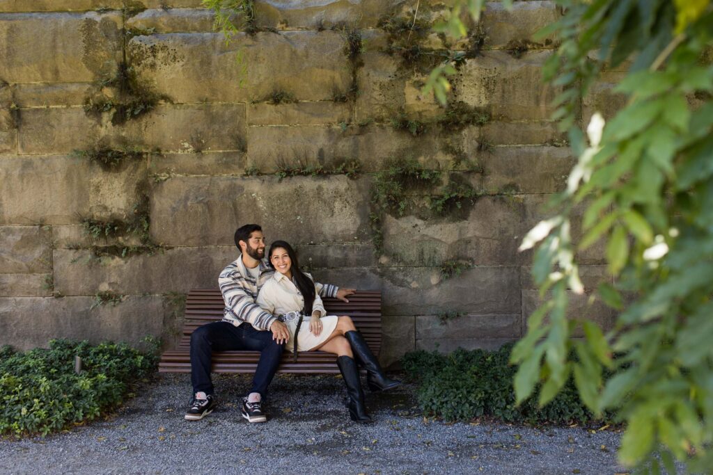 engaged couple sits on bench together at the biltmore estate after their surprise proposal