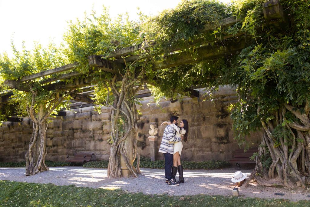 engaged couple kisses under wisteria vines at the biltmore estate in the fall