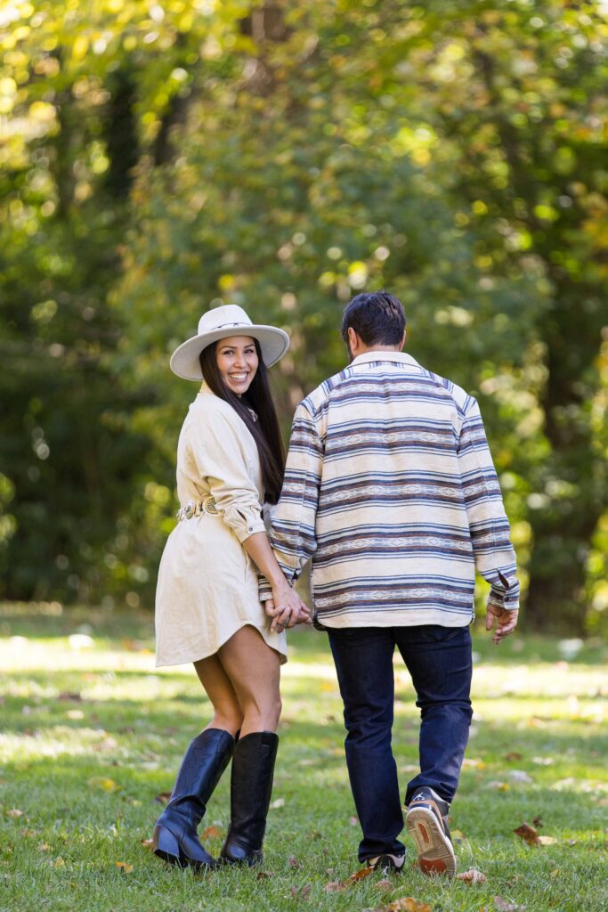 woman looks over her shoulder as she walks away with her new fiance on the day of their surprise proposal at the biltmore estate