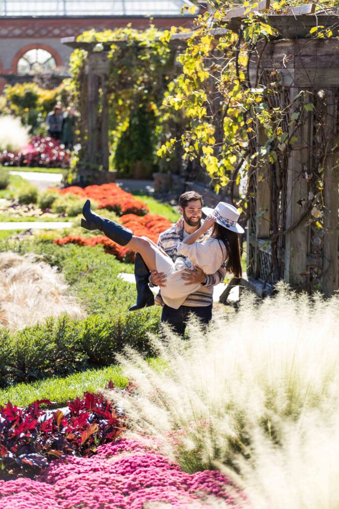 man picks up woman in the gardens after their surprise proposal at the biltmore estate