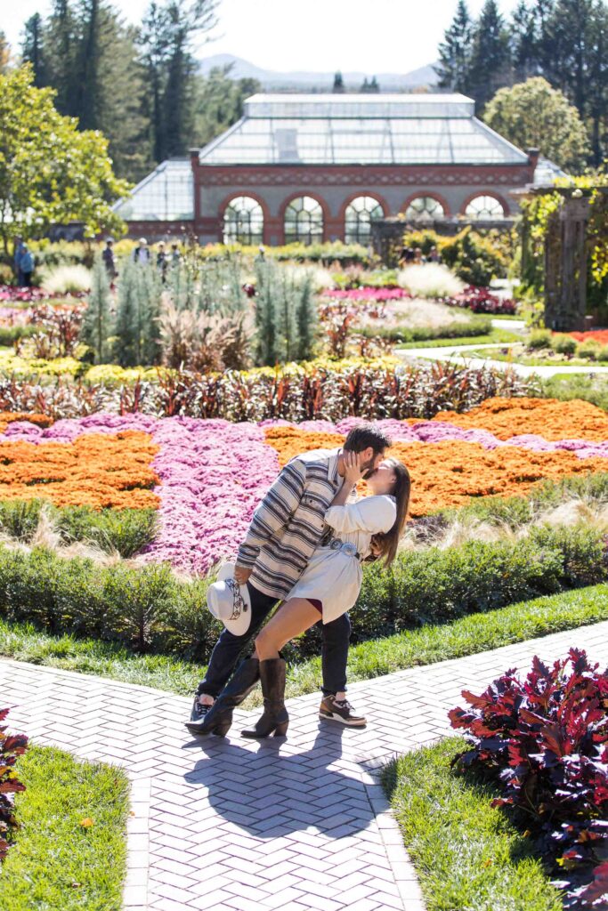 man dips woman and kisses her in the Biltmore estate gardens during the fall