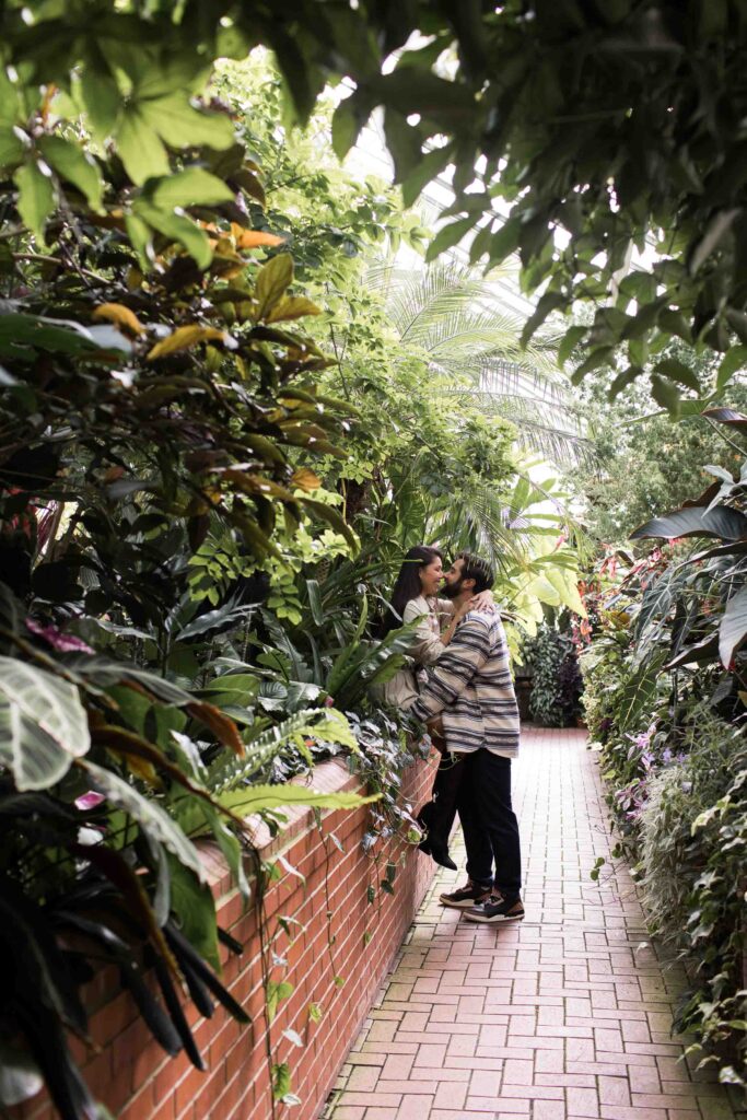 couple kisses in the biltmore estate conservatory framed by tropical plants