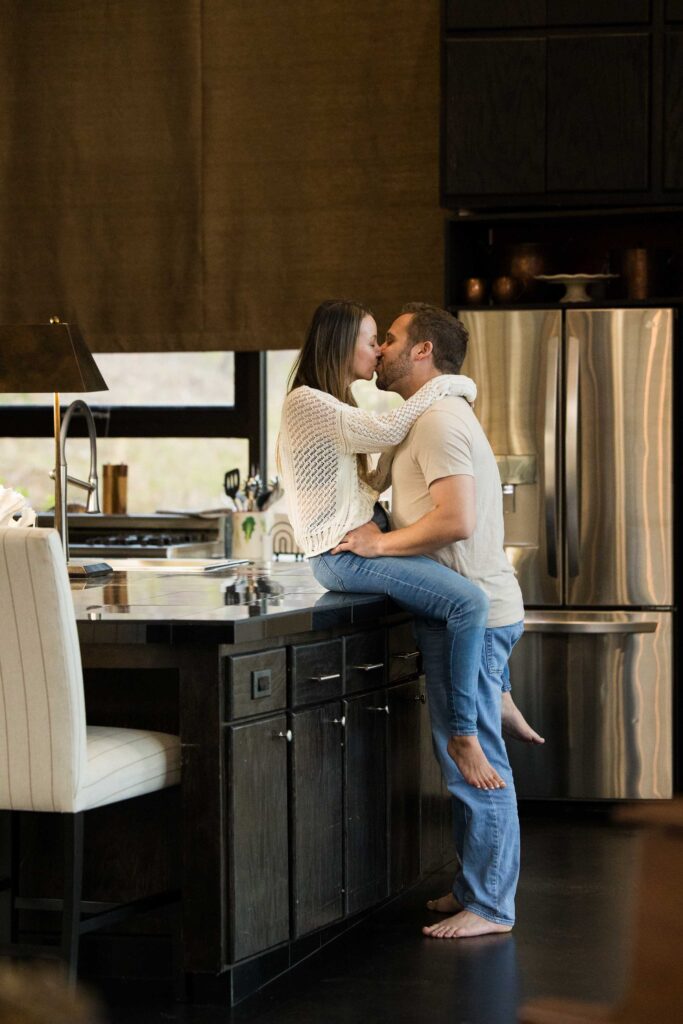 couple kisses while the woman sits on the kitchen counter