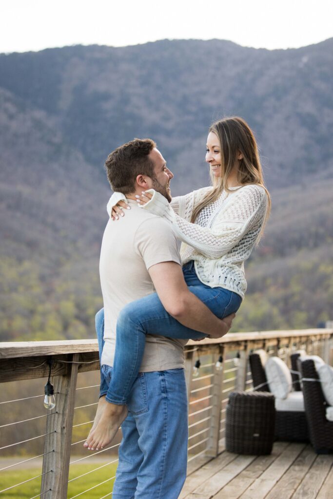 a man picks up and embraces his partner at the redstone mansion during their romantic lifestyle session the day before their nc mountain elopement