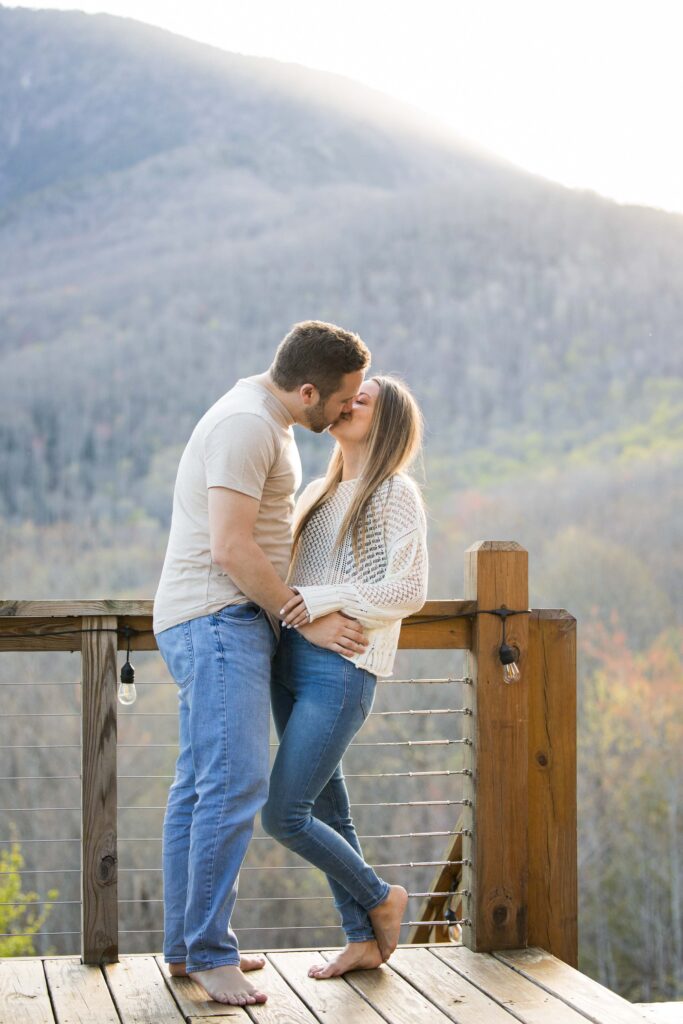 couple kisses on a porch in the blue ridge mountains of north carolina 