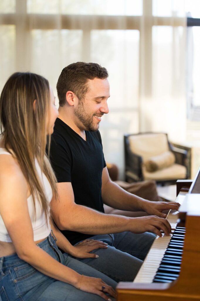 a man smiles and plays piano for his partner at their airbnb the redstone mansion