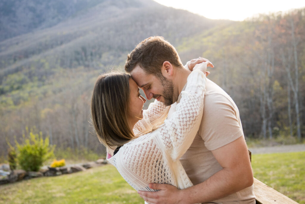 couple embraces in the glow of the setting sun with a mountain backdrop at the redstone mansion in burnsville