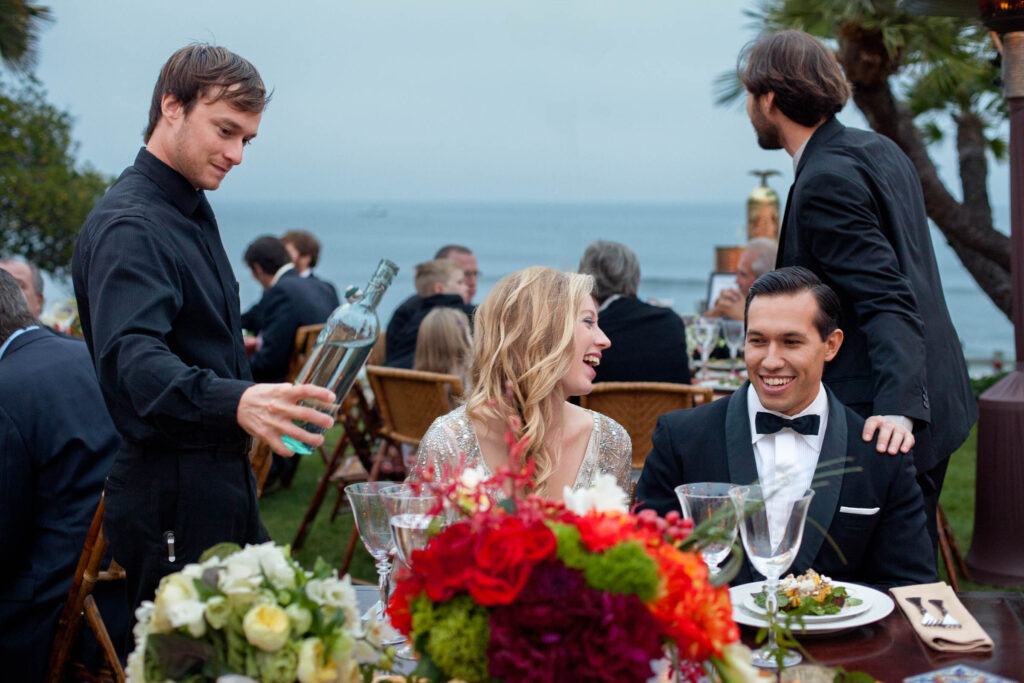 married couple having dinner at their wedding in malibu at the adamson house with the Pacific ocean behind them