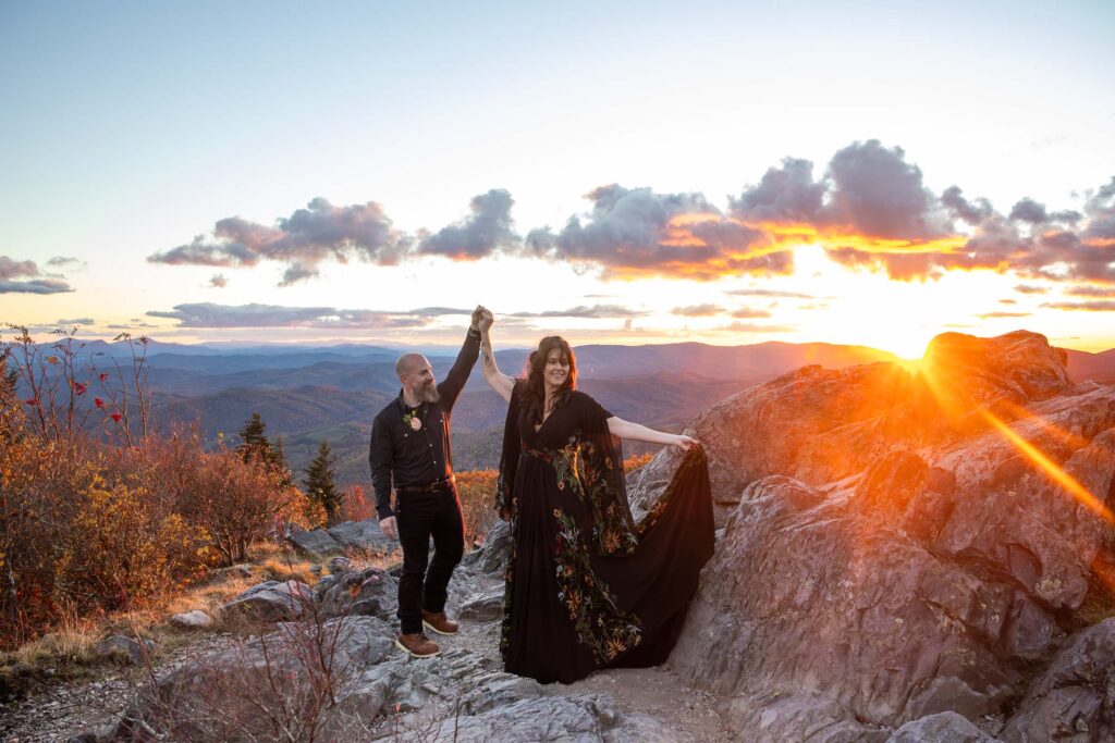 Couple dancing on a mountaintop during sunset with rays of golden light shining at their Grayson Highlands hiking elopement
