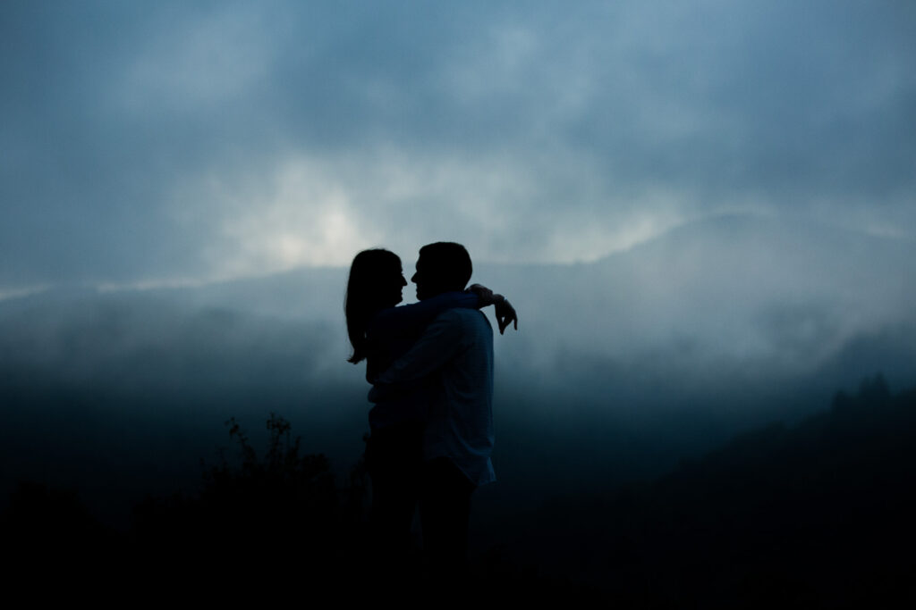 couple embracing at sunset in the fog on the blue ridge parkway