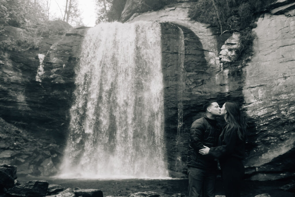 Romantic couple kissing during an engagement session at Looking Glass Falls in Pisgah National Forest, Brevard NC.