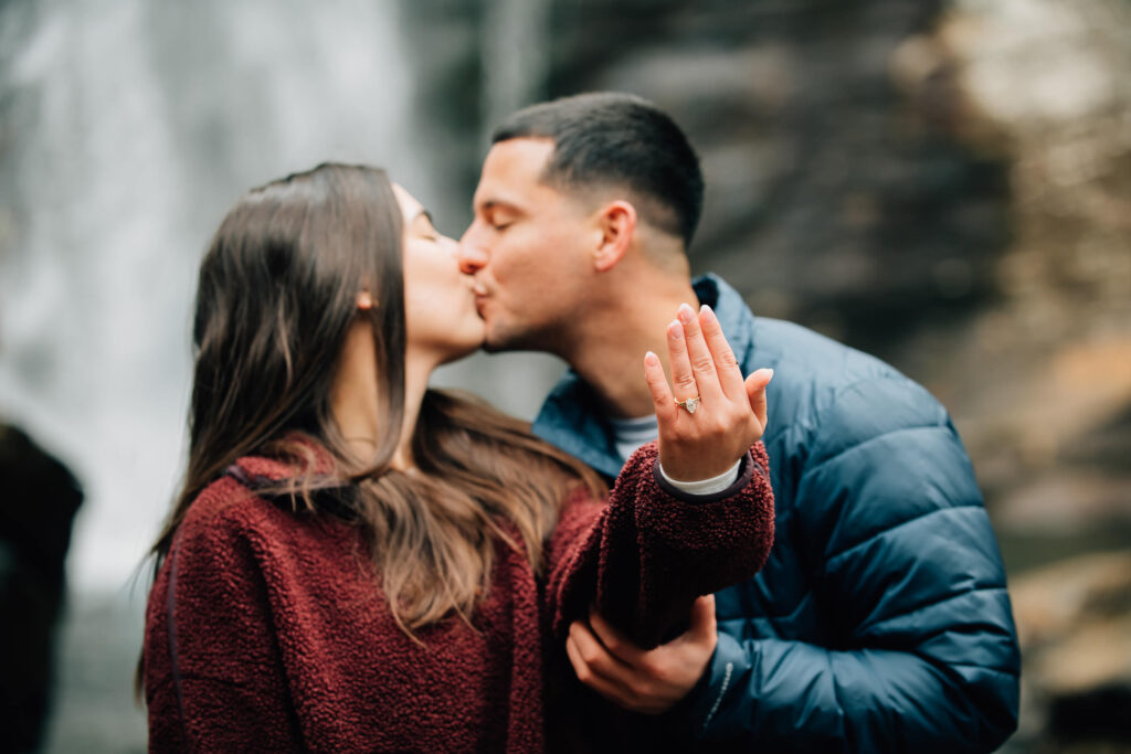 Close-up of engagement ring during a surprise proposal at Looking Glass Falls near Brevard, North Carolina, surrounded by forest and waterfall views.