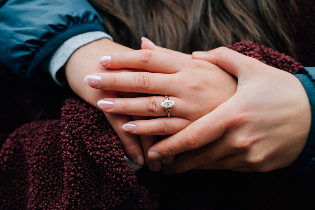 Close-up of engagement ring during a surprise proposal at Looking Glass Falls near Brevard, North Carolina, surrounded by forest and waterfall views.