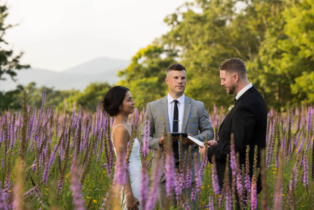 officiant marrying a couple in a wildflower field in the mountains of north carolina during elopement ceremony
