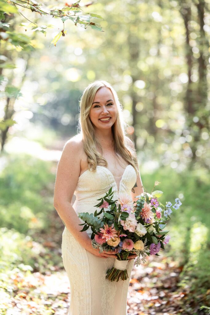 NC elopement bride surrounded by trees on a trail at Pilot Mountain State Park