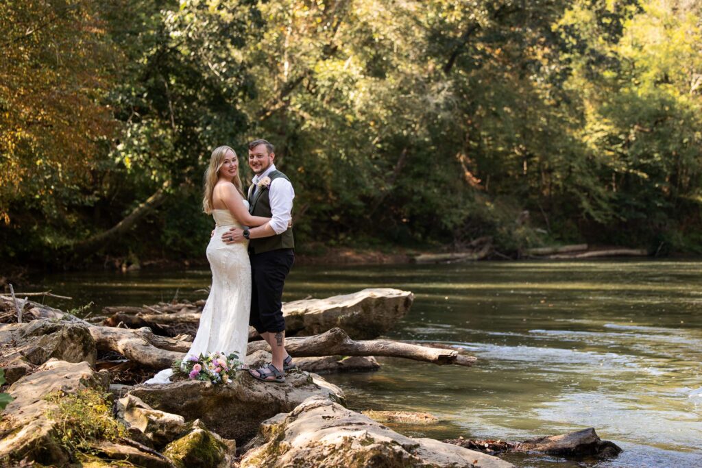 Pilot Mountain State Park elopement on the Yadkin River in North Carolina with a couple standing on river rocks surrounded by trees