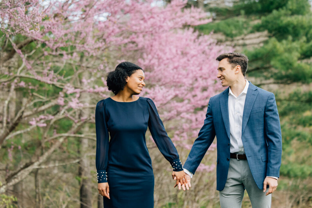 couple holds hands after their proposal with a colorful spring backdrop at the arboretum in asheville