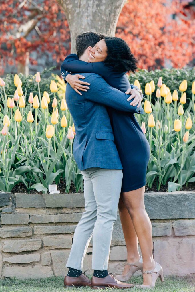 woman hugs her fiance after she says yes to his proposal at the unc arboretum 