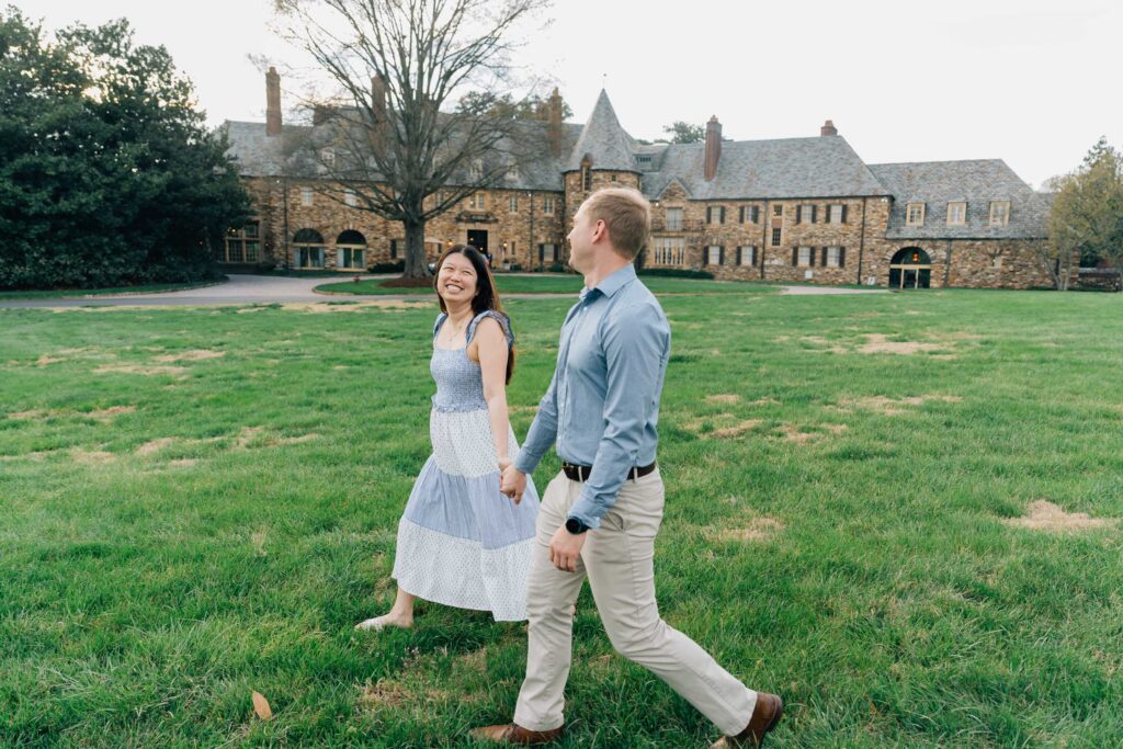 engaged couple walks in front of the graylyn estate manor house in winston salem nc after their surprise proposal