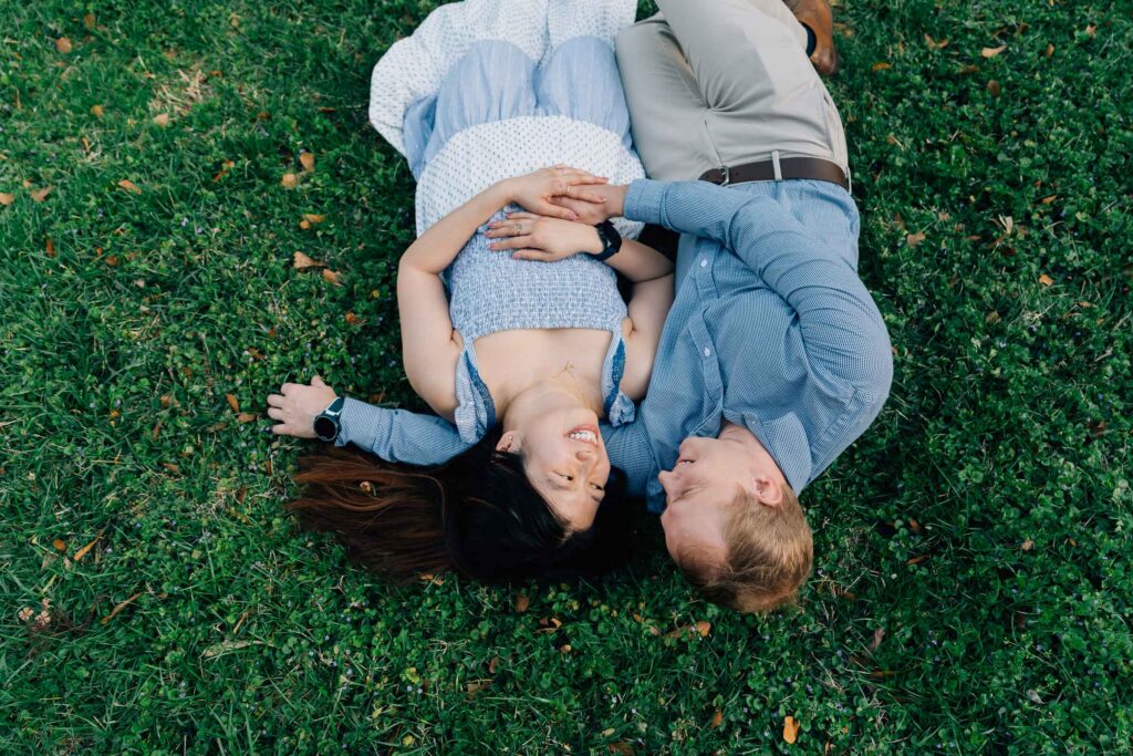 engaged couple lays in the grass at the graylyn estate after their proposal