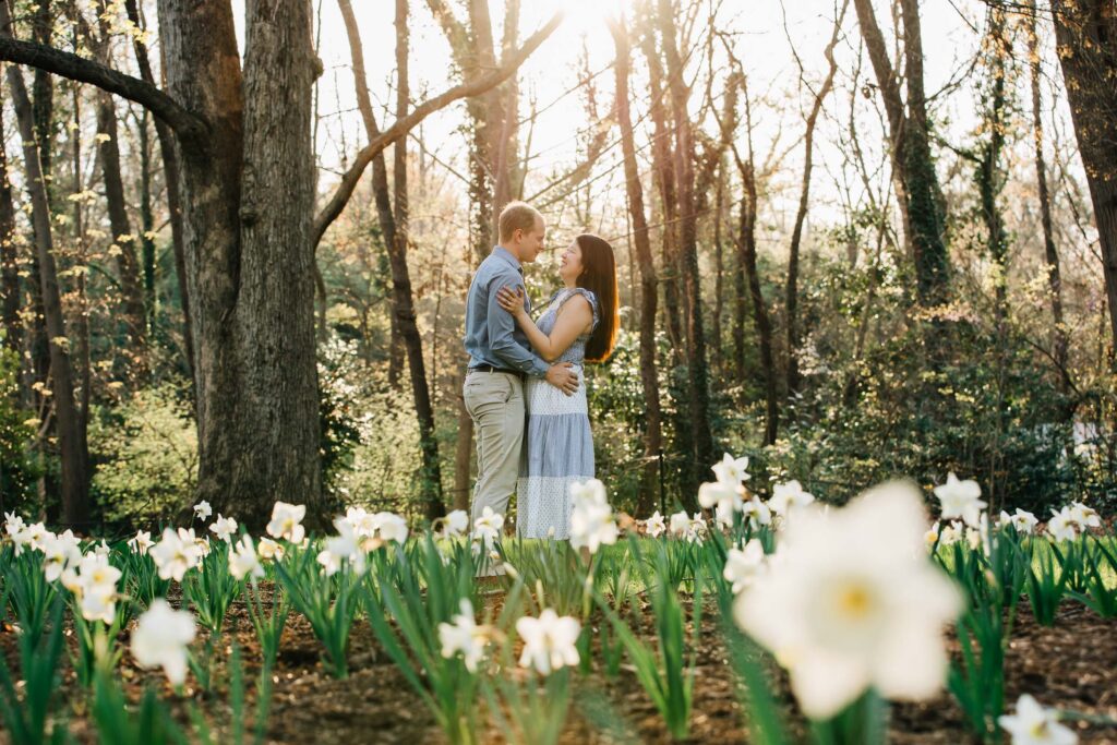 engaged couple amongst daffodils in the gardens at the graylyn estate in winston-salem, nc after their surprise proposal