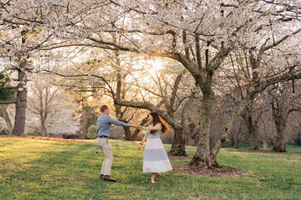 couple dances under cherry blossoms at the graylyn estate in winston-salem, nc after their surprise proposal