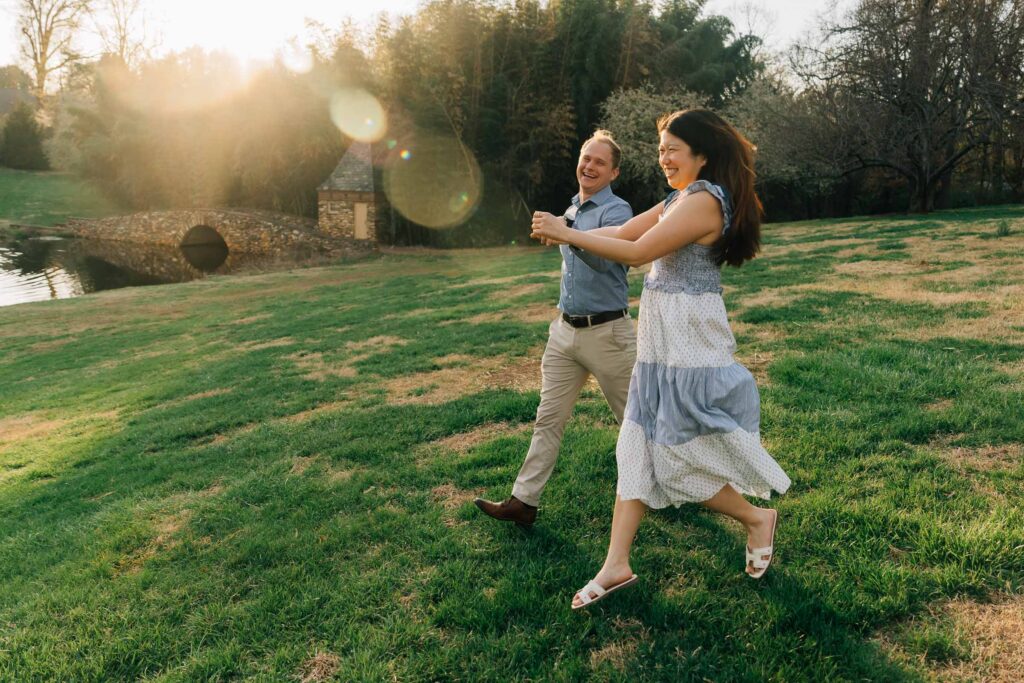 woman jumps for joy as she holds hands with her new fiance after their surprise proposal at the graylyn estate in winston-salem, nc