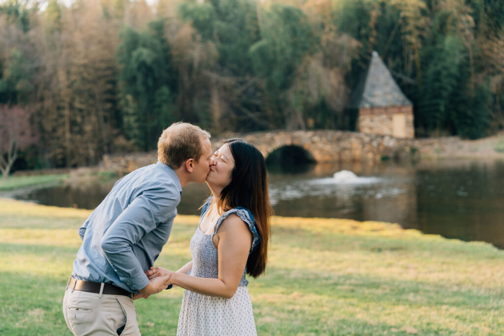 couple kisses after their engagement in front of the bridge at the graylyn estate in nc