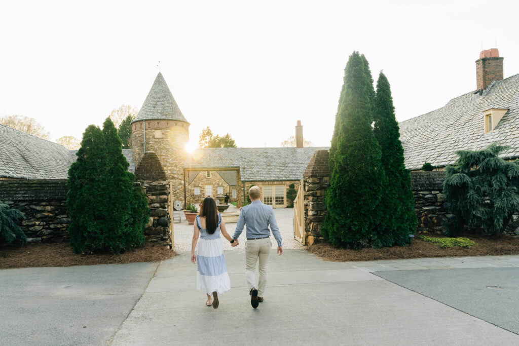 engaged couple walking toward the mews at sunset after their proposal at the graylyn estate in nc