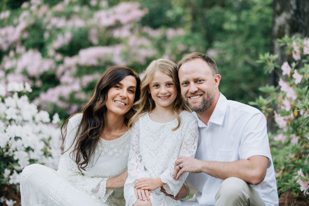 family smiles amongst the white and pink azaleas blooming in hurley park during the spring