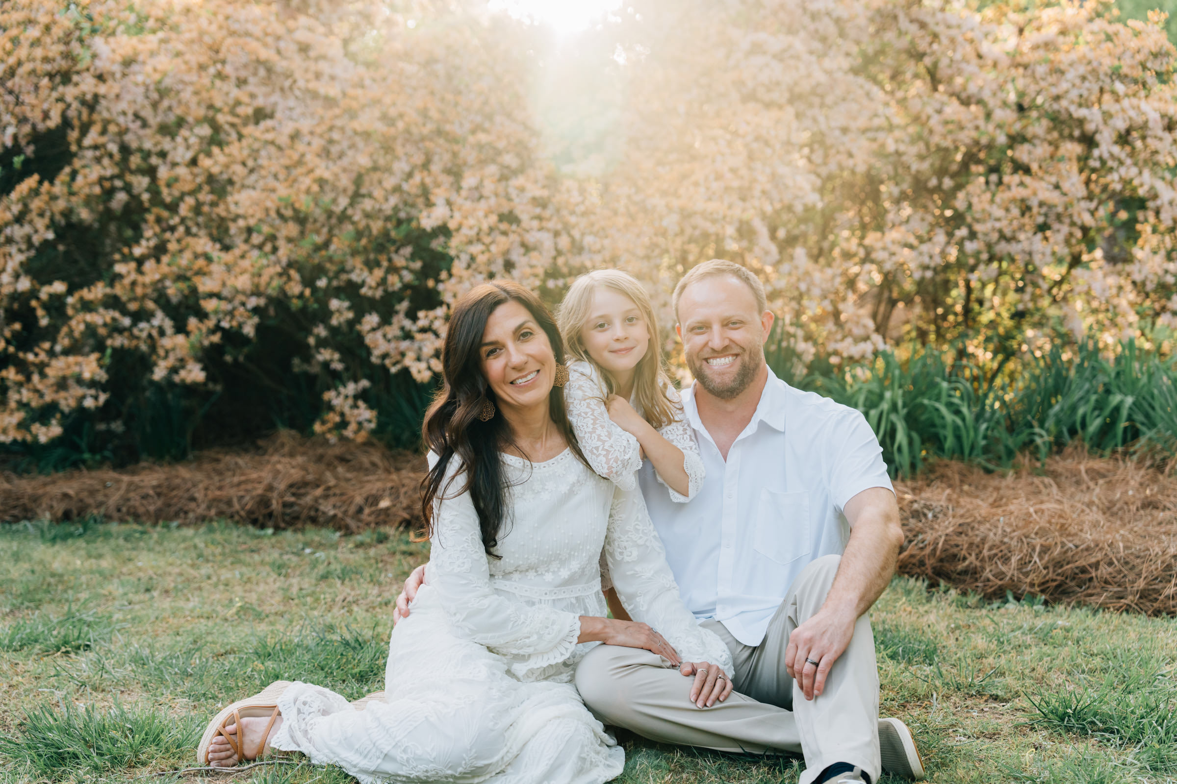 family cuddles while sitting in the grass at golden hour amongst the blooming azaleas at hurley park in salisbury