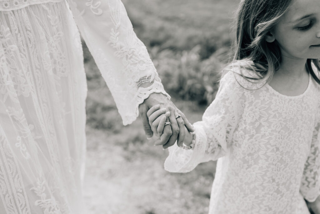 black and white closeup of a little girl holds her mom's hand