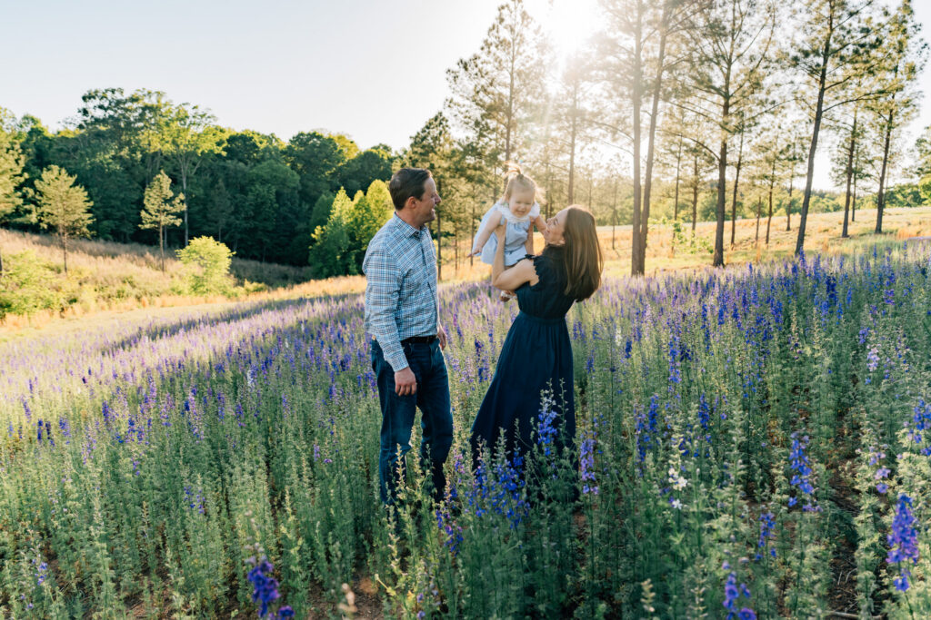 parents play with their toddler and toss her in the air during golden hour at dogwood farms