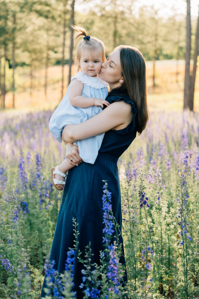 mom kisses her toddler daughter at dogwood farms during sunset 
