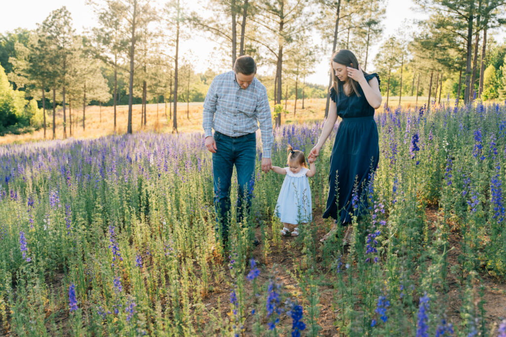 family walks through purple larkspur flowers at dogwood farms in nc