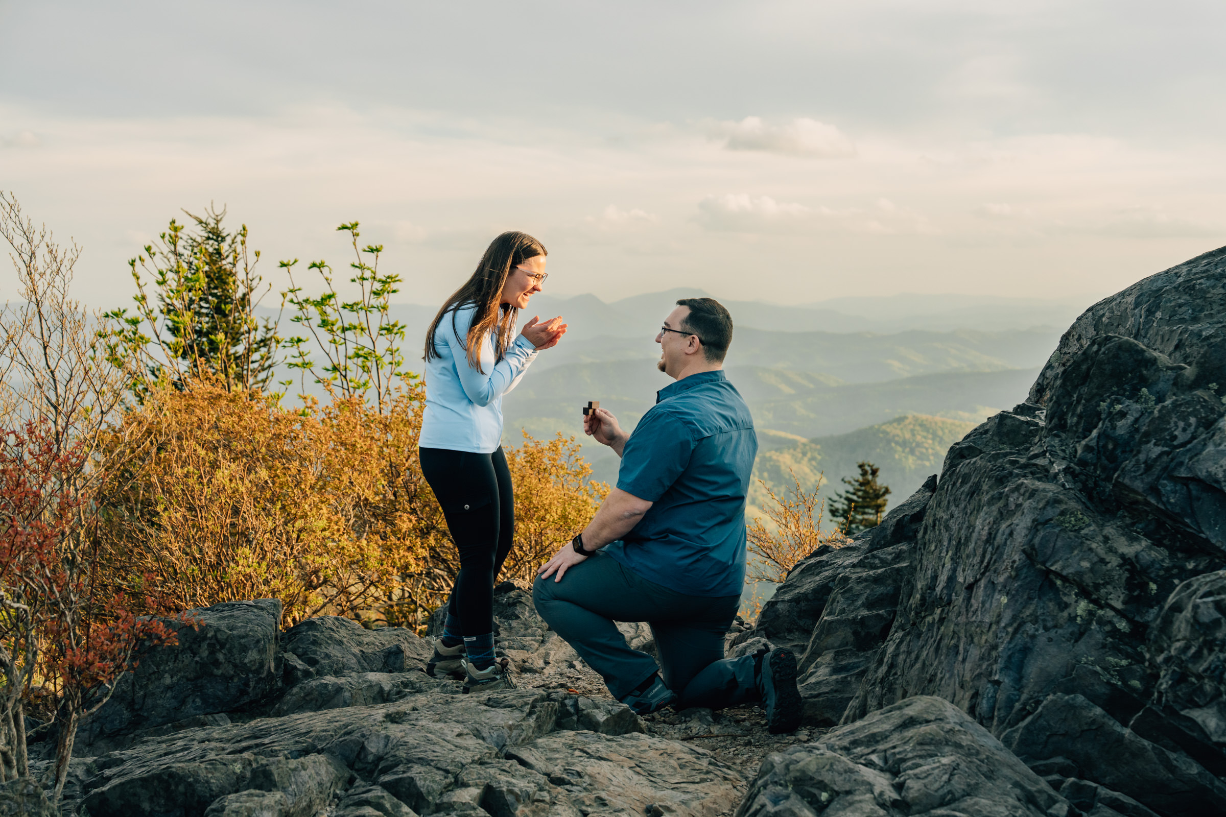 man proposes on one knee to his girlfriend at grayson highlands state park in virginia with mountains in the background at sunset