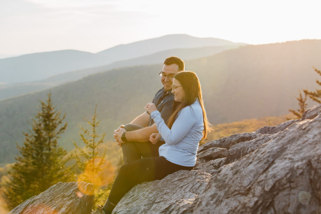 couple sits on a rock with an epic mountain sunset view at golden hour in grayson highlands state park