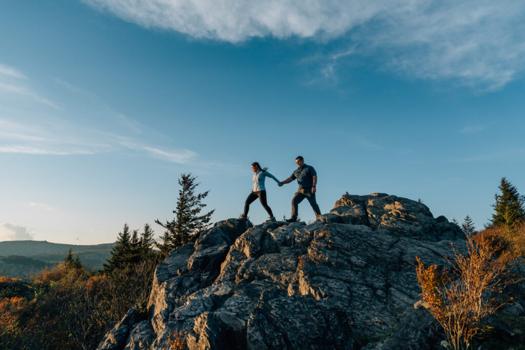 couple holding hands and walking along a rocky peak at Little Pinnacle in Grayson Highlands State Park