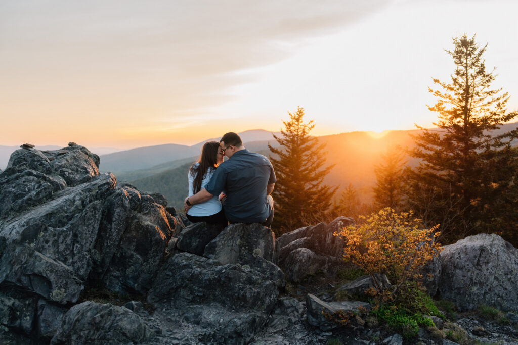 couple sits on a rock during sunset at Grayson Highlands State Park after their surprise proposal