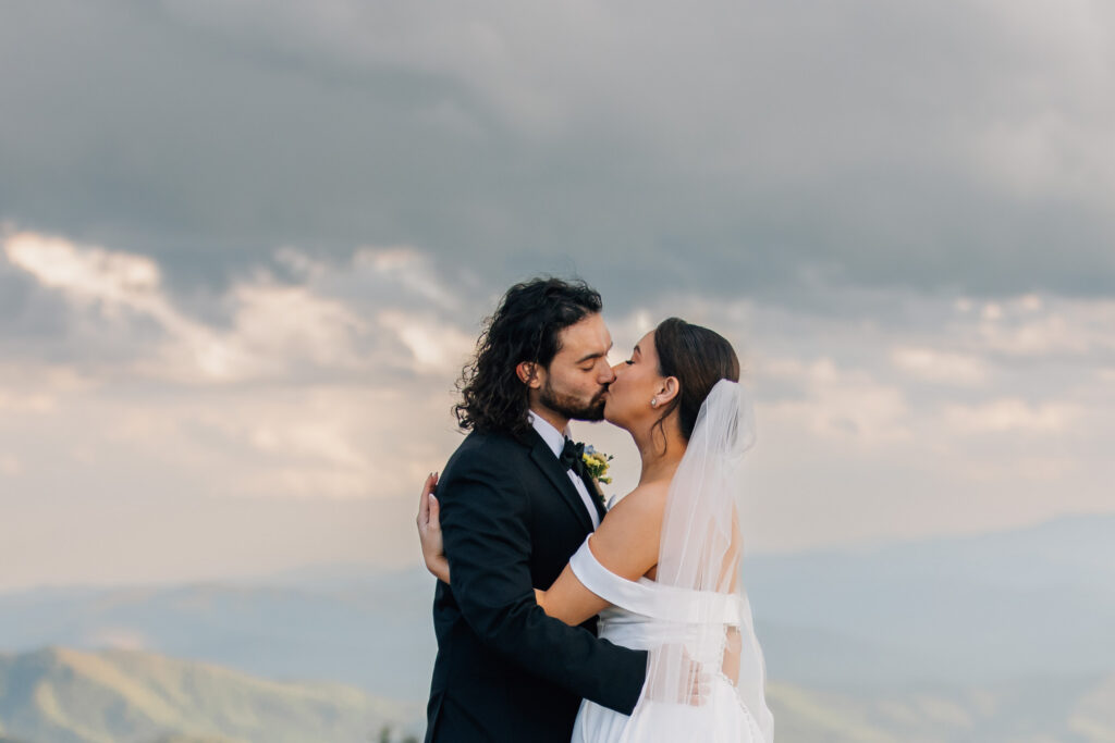 couple kisses with the mountains and sky as a backdrop during their mountain elopement in nc