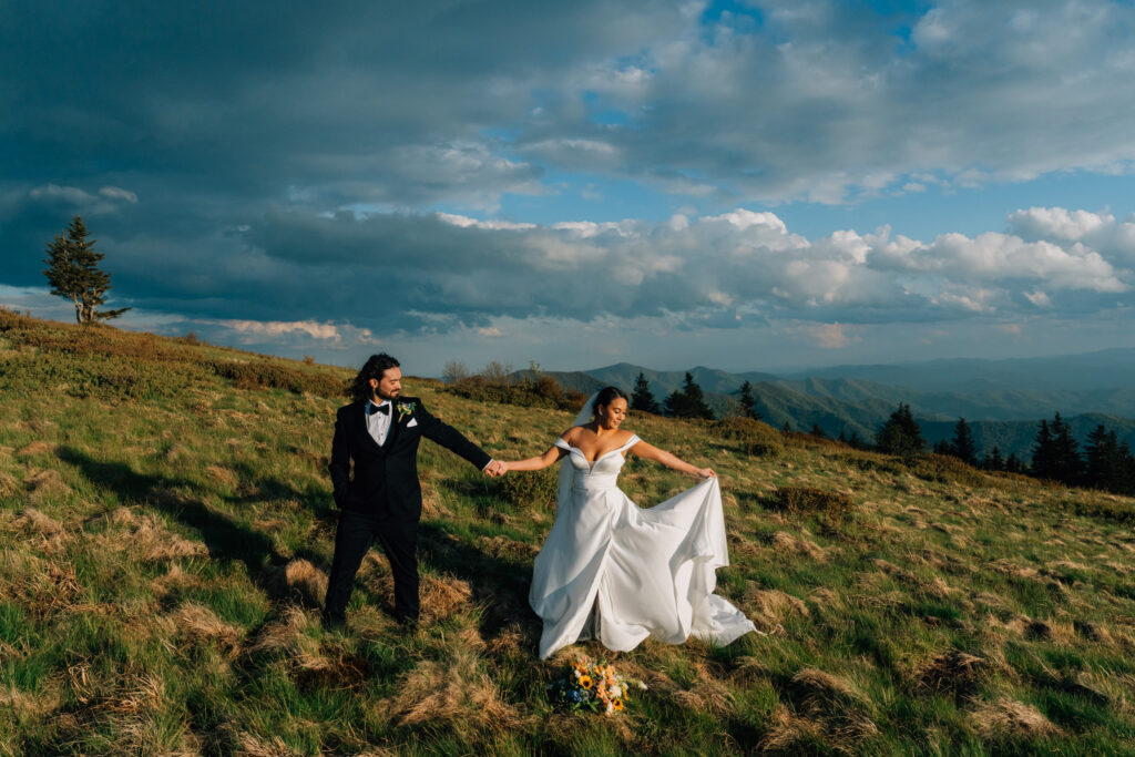 married couple stands on a windy grassy bald at roan mountain in nc during golden hour after their sunset elopement