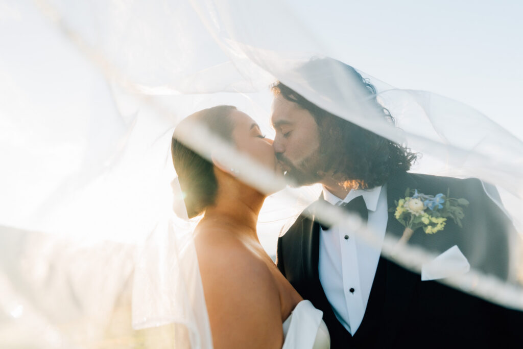 cinematic photo of golden light filtering through the bride's veil as she shares a kiss with her new husband during their roan mountain elopement
