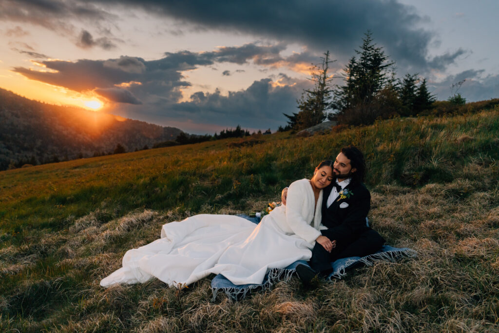 couple cuddles on a blanket as the sun sets during their roan mountain elopement