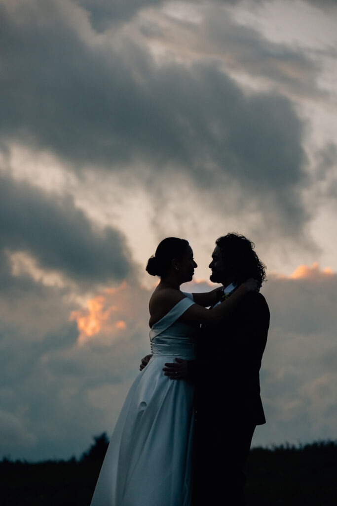 silhouetted couple against a stormy sunset sky at carver's gap in the roan highlands