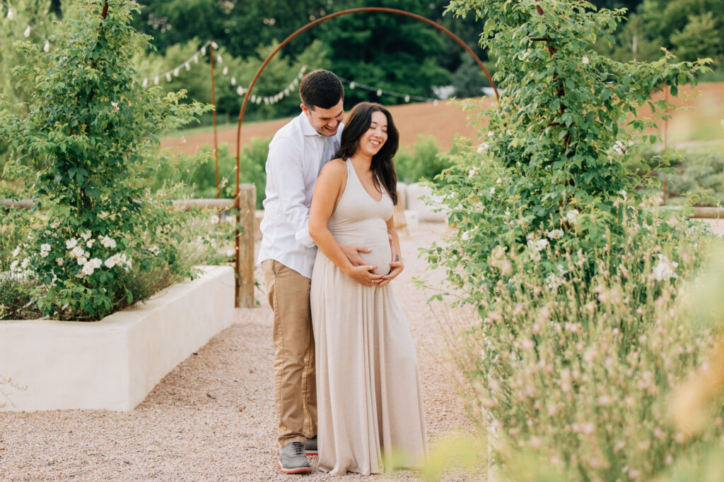 couple holds hands outside fleurish greenhouse during maternity session