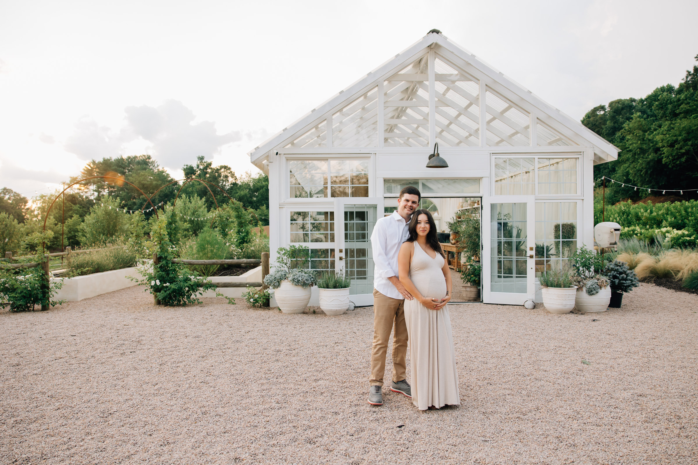 couple holds hands outside fleurish greenhouse during maternity session