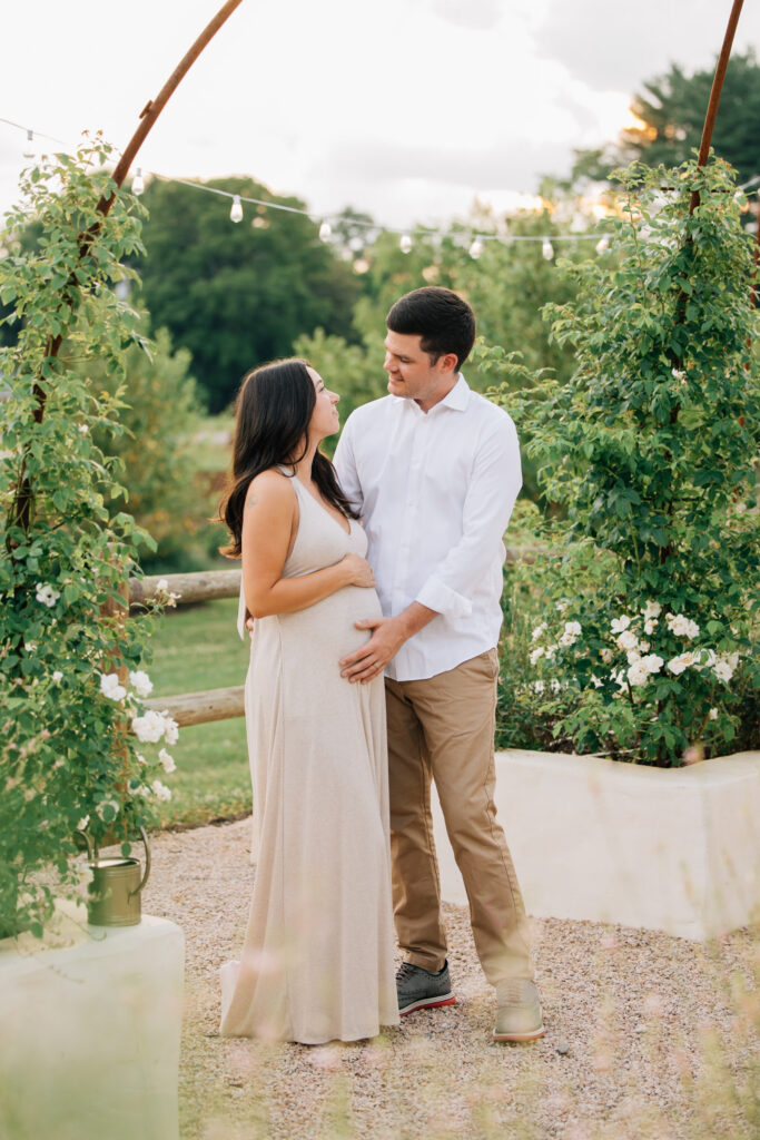 couple holds hands outside fleurish greenhouse during maternity session